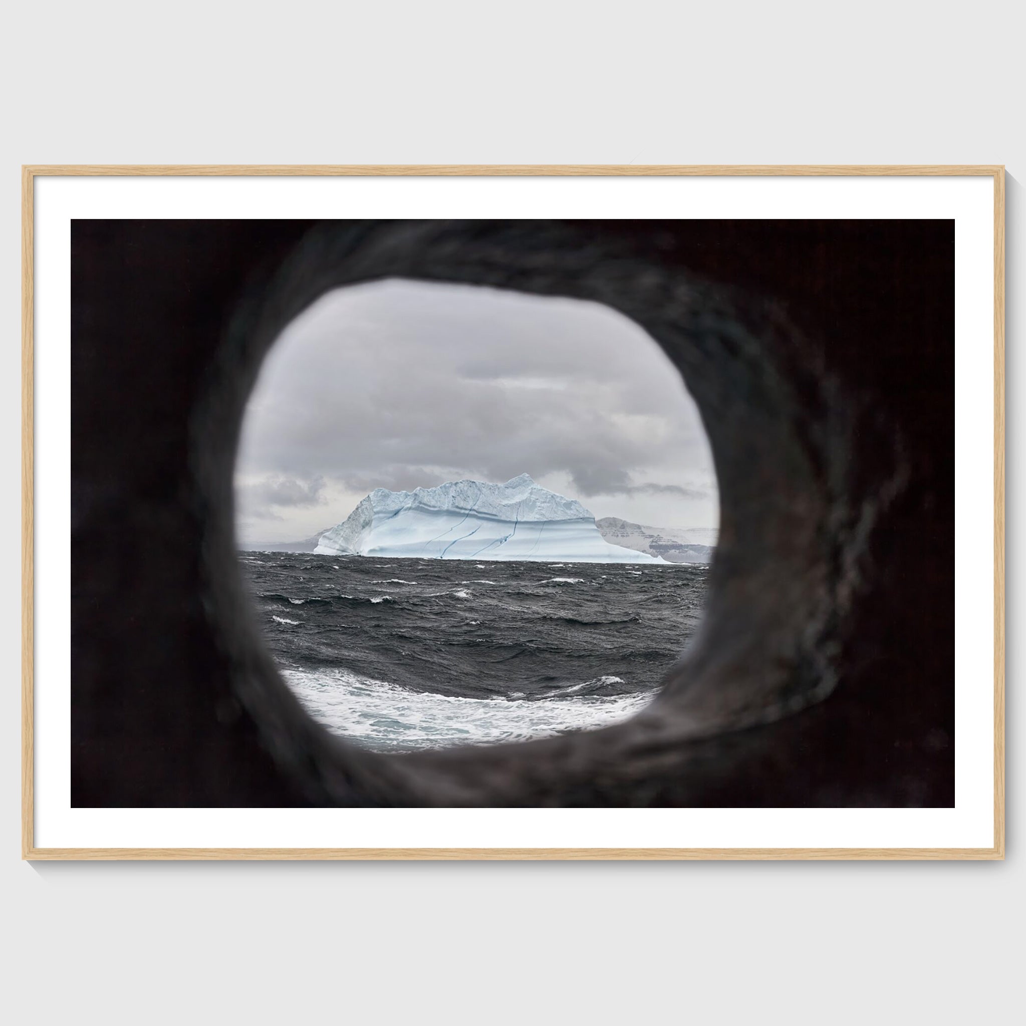Colour photograph of an iceberg viewed through a ship’s scupper, shown in an oak frame, Greenland