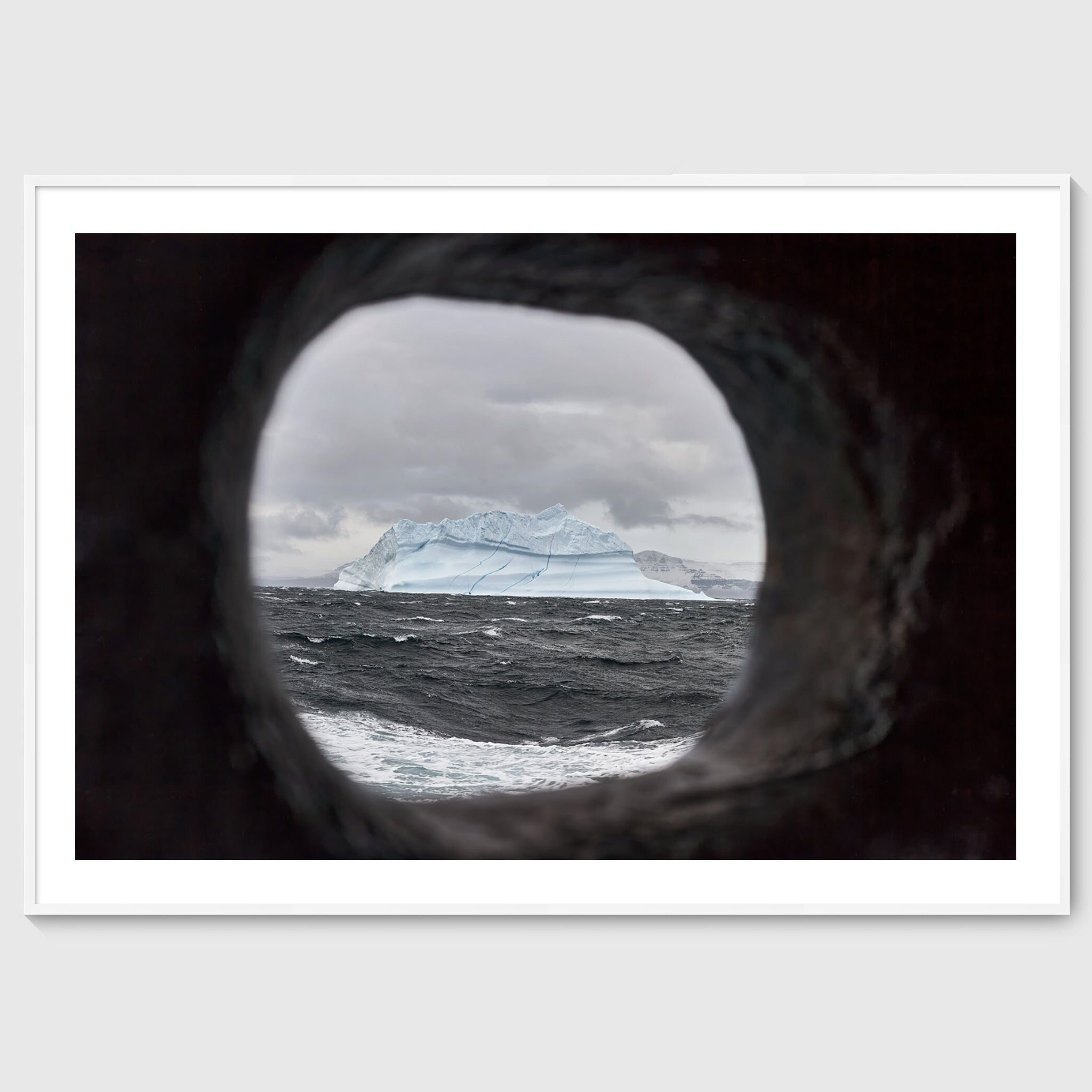 Colour photograph of an iceberg viewed through a ship’s scupper, shown in a white frame, Greenland