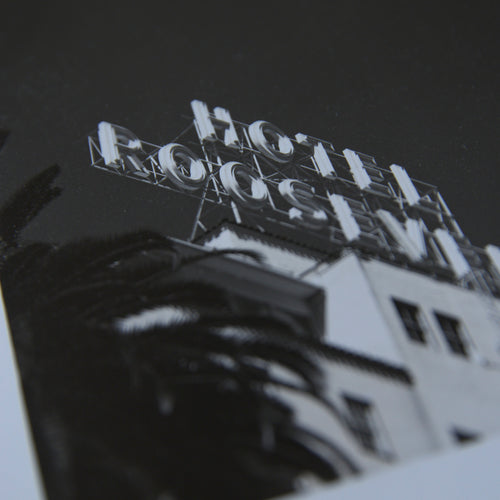 Details of a one-off black and white darkroom photograph of a hotel rooftop sign and palm tree against a cloudless sky, hand-printed by the artist.