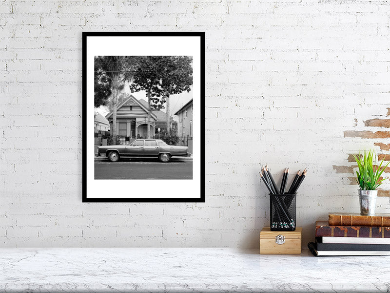 Black and white photograph of a residential street scene displayed in a styled interior desktop setting (mockup)