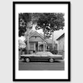 Black and white photograph of a parked car in front of a suburban house, California shown in a black wood frame