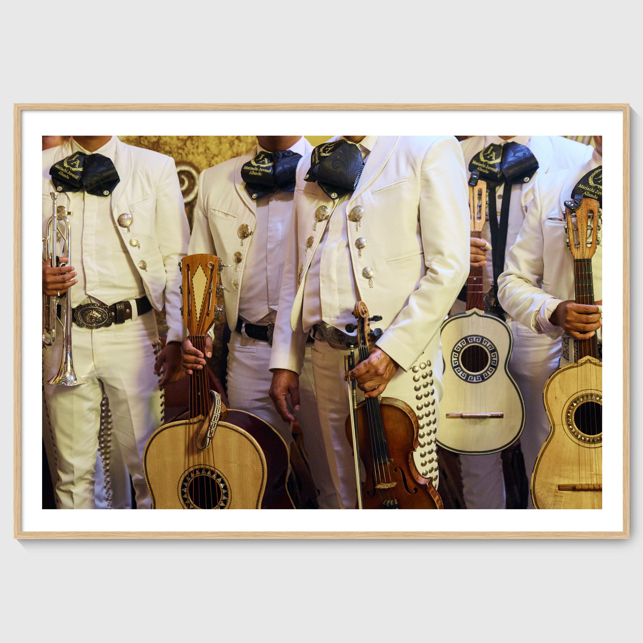 Colour photograph of mariachi musicians wearing traditional white charro suits and holding instruments in San Miguel de Allende, shown in an oak wooden frame