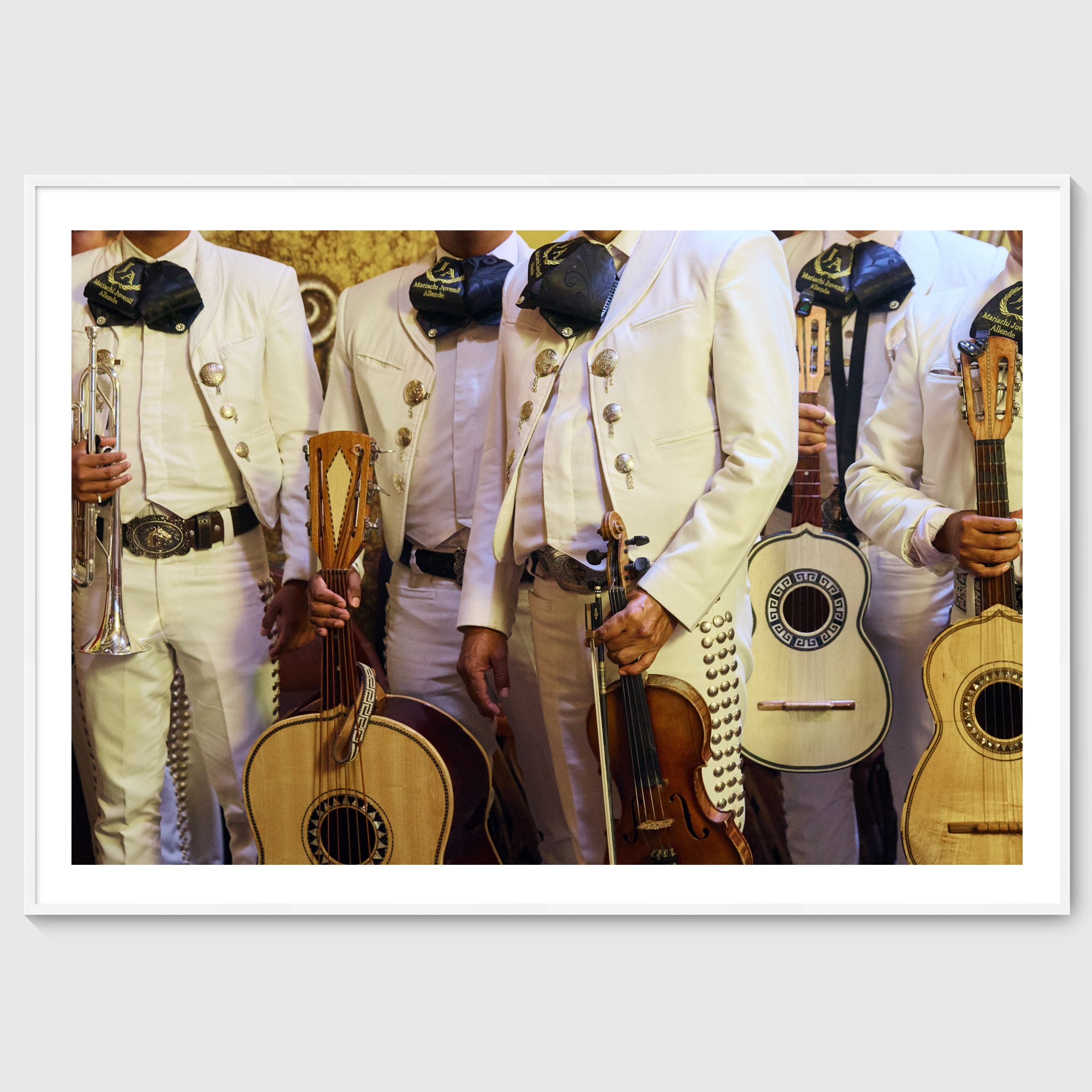 Colour photograph of mariachi musicians wearing traditional white charro suits and holding instruments in San Miguel de Allende, shown in a white wooden frame