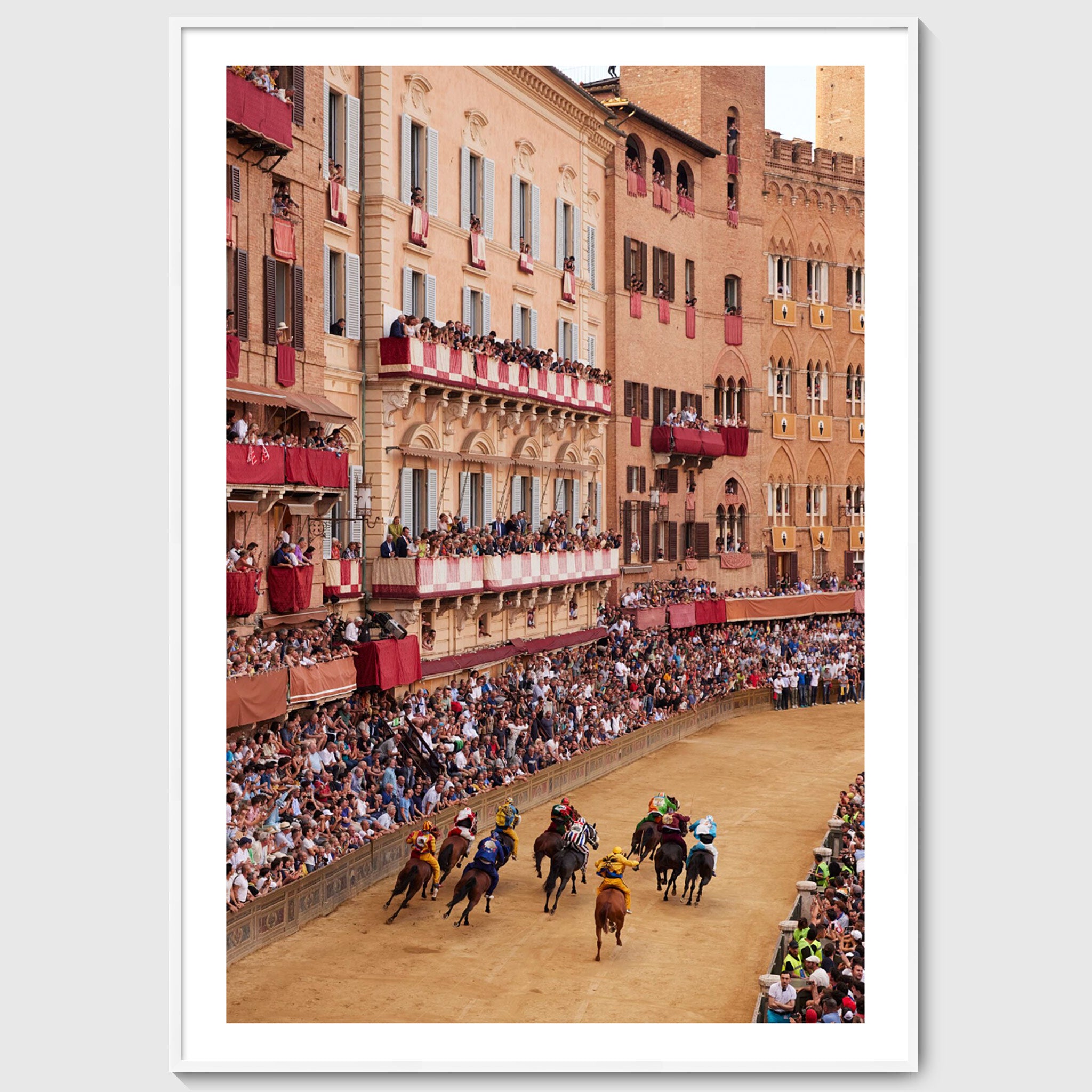 Colour photograph of Piazza del Campo filled with spectators as horses race past historic buildings during the Palio di Siena, sold as an unframed fine art print