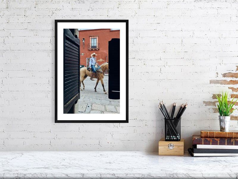 Colour photograph of a horse and rider framed within a doorway displayed as a small  framed print in a styled interior desktop setting (mockup)