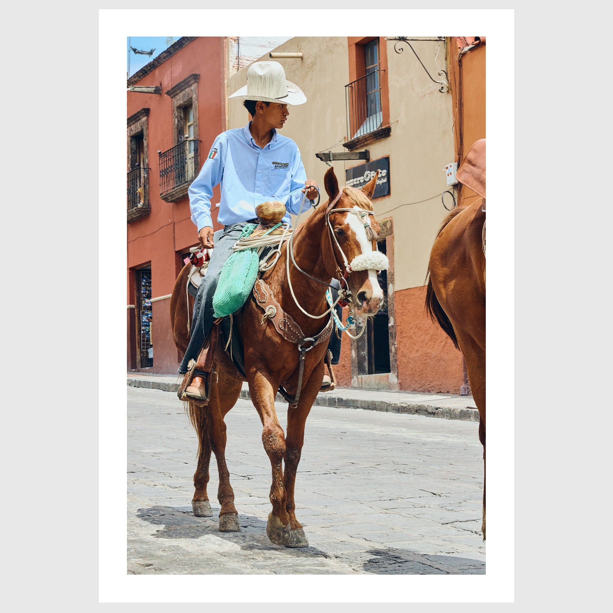 Colour photograph of a young vaquero riding a horse through the streets of San Miguel de Allende, sold as an unframed fine art print